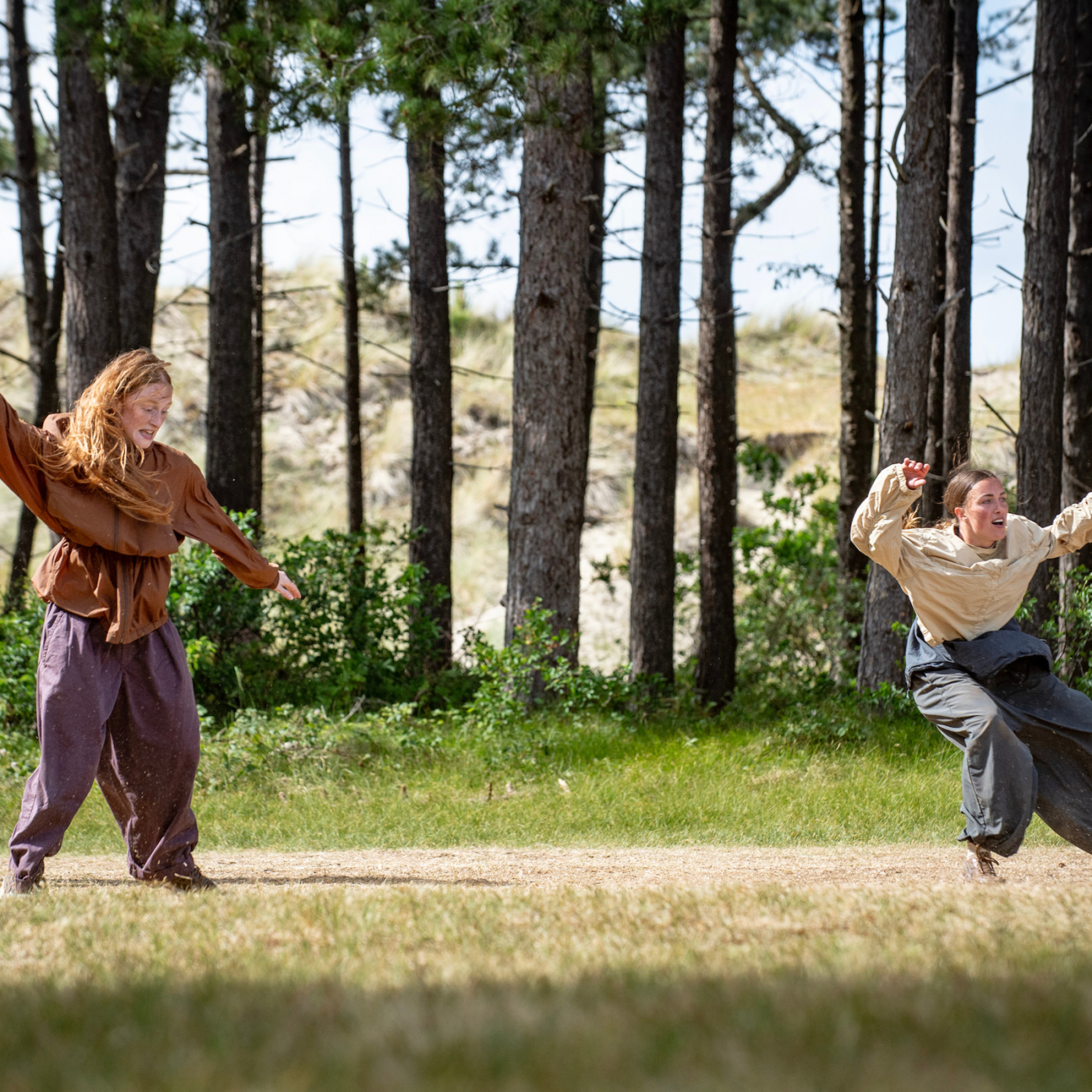 Danstheater AYA&Anne Suurendonk met de voorstelling Spiral tijdens Oerol 2026. Drie jonge dansers met bomen op de achtergrond. foto: GeertSnoeijer